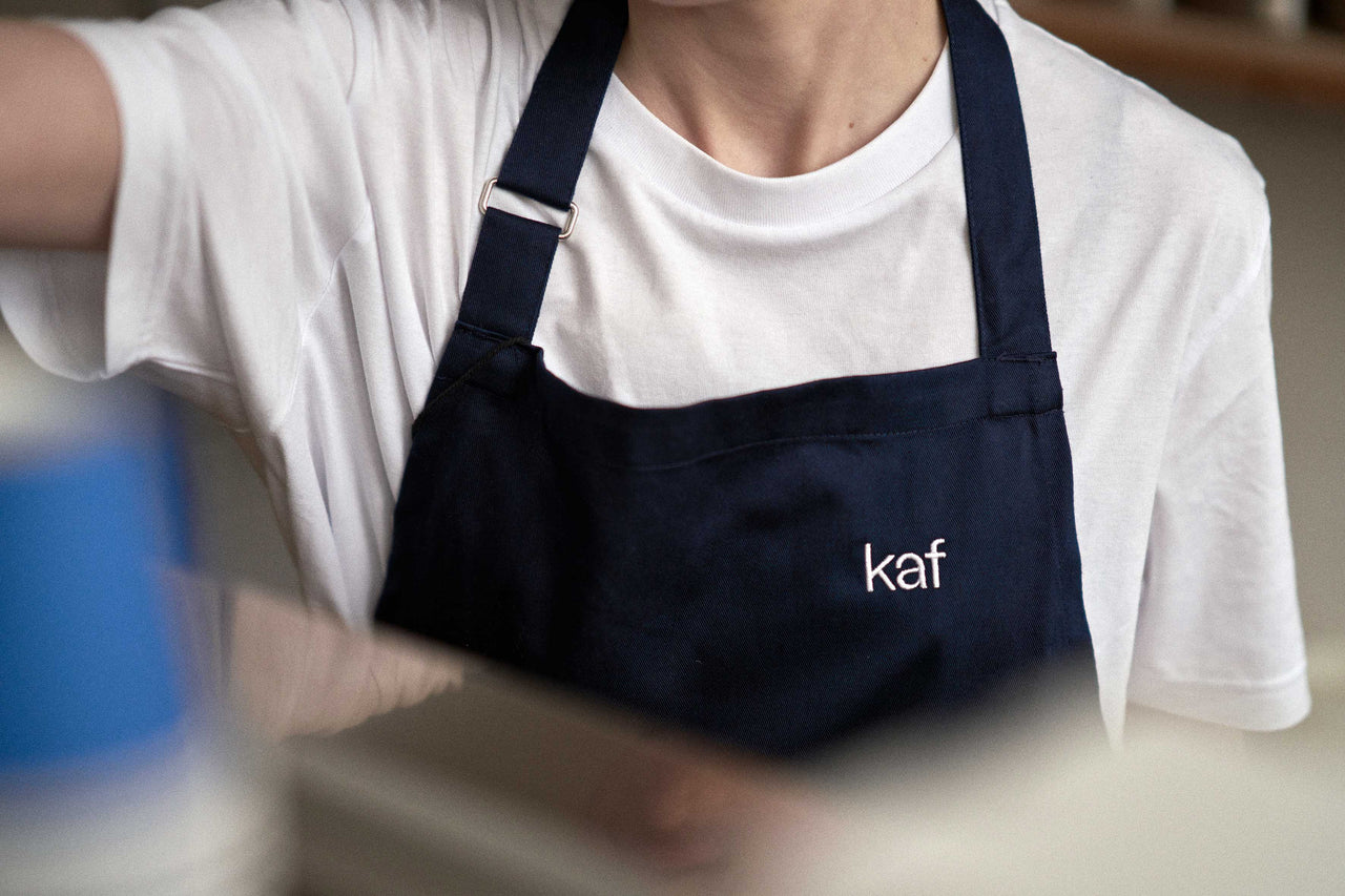 barista wearing navy kaf branded apron.