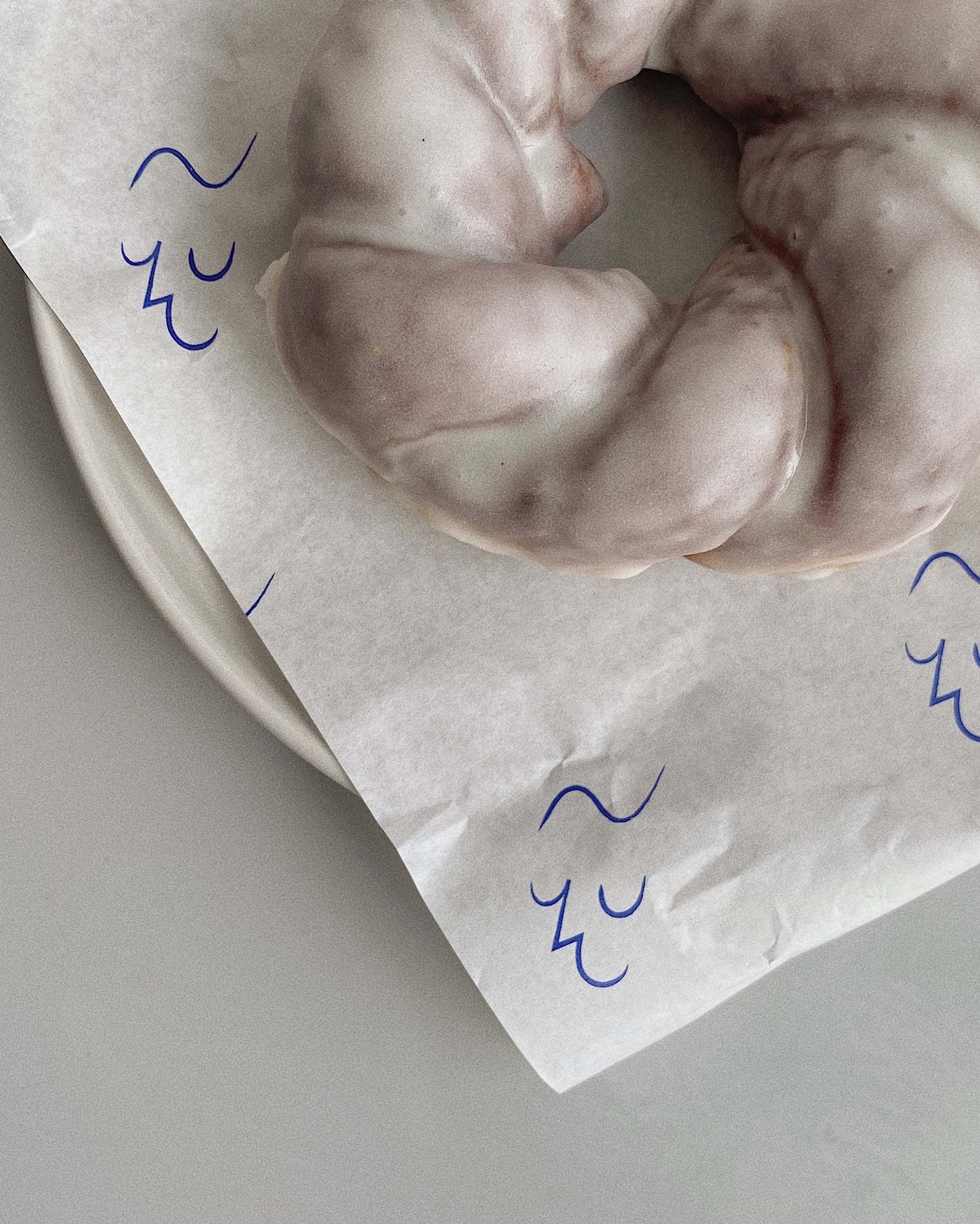 kaf glazed vanilla twisty doughnut on logo branded greaseproof.