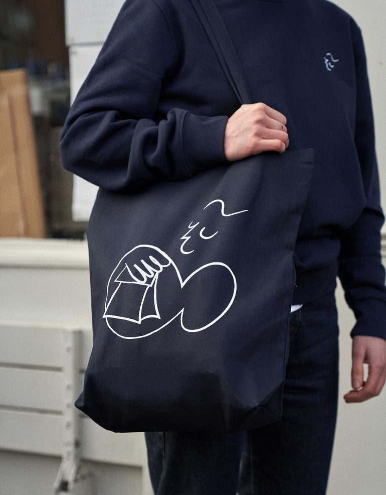 person wearing all navy wearing kaf branded tote bag and jumper.